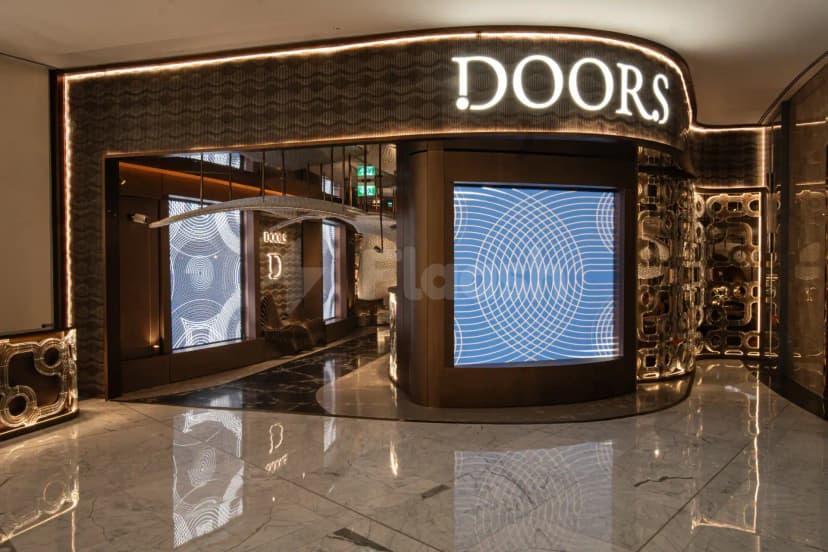 Entrance hall of Doors Dubai Mall Restaurant featuring a curved illuminated sign, textured wall panel, and a blue