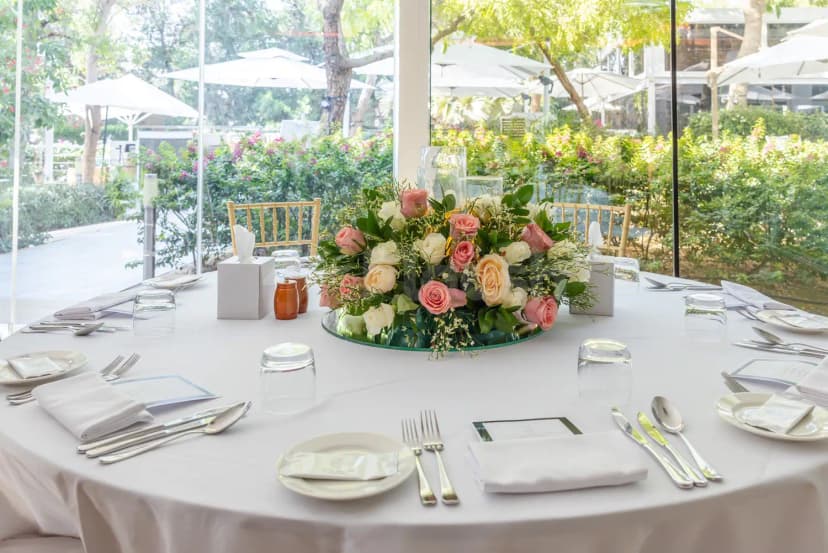 Round dining table at The Farm Restaurant Al Barari in Dubai, featuring a floral centerpiece and large windows