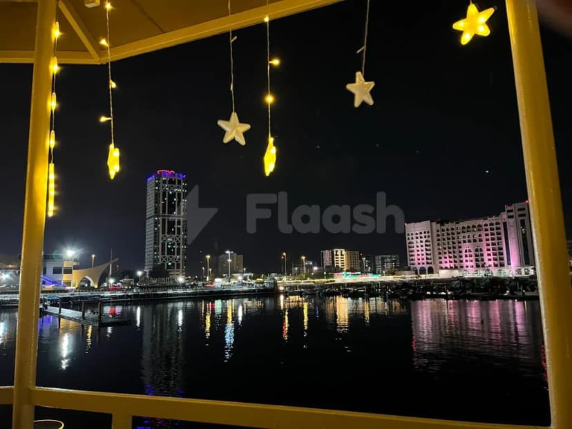 Rooftop terrace at The Sailors Fujairah with yellow metal railing, hanging star and cylindrical lights, overlooking marina