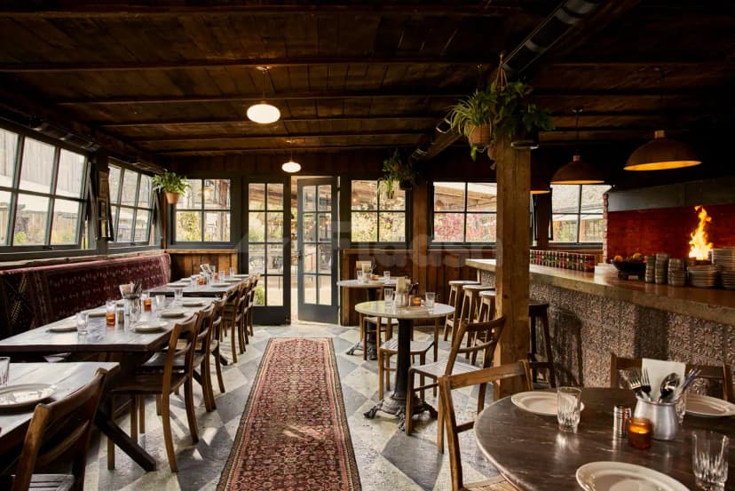 Rustic restaurant interior at Berenjak Acurio Restaurant Dubai featuring a wooden ceiling, checkered tile floor, and a long