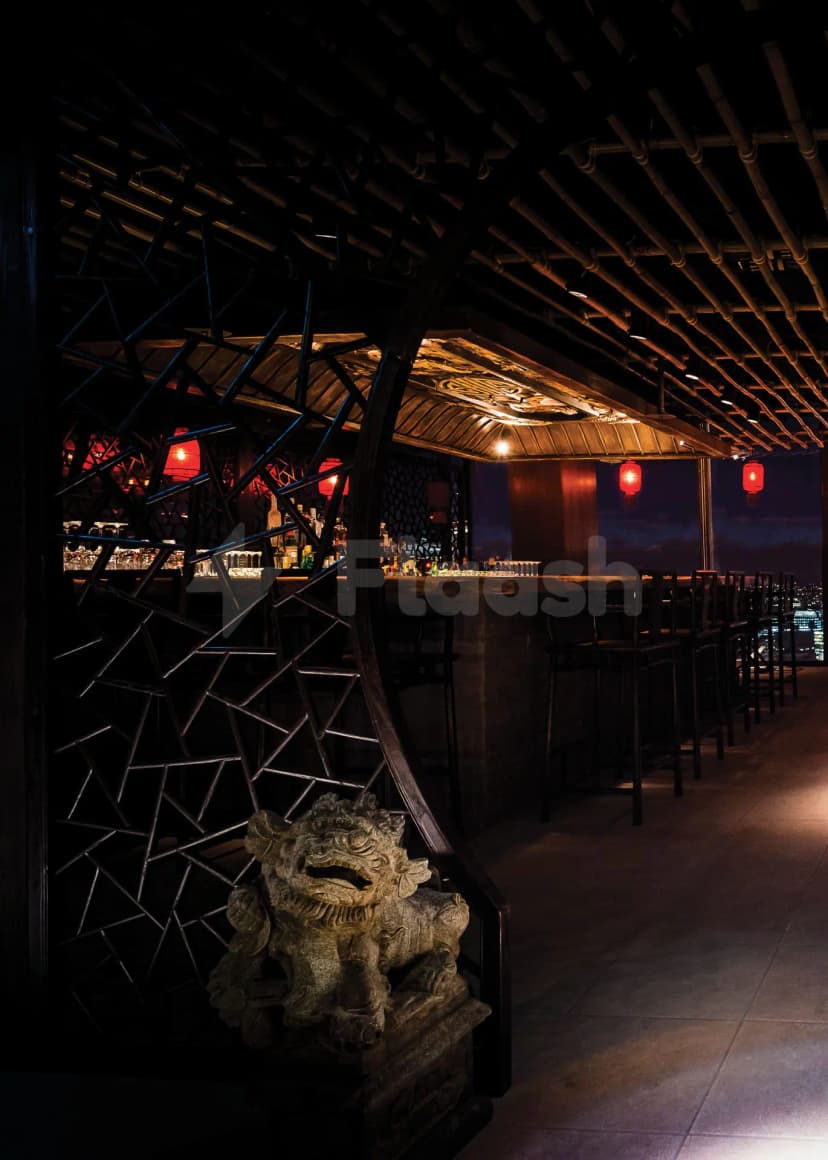 Rooftop terrace at Hutong Dubai featuring a stone lion statue and black metal lattice screen with warm lighting