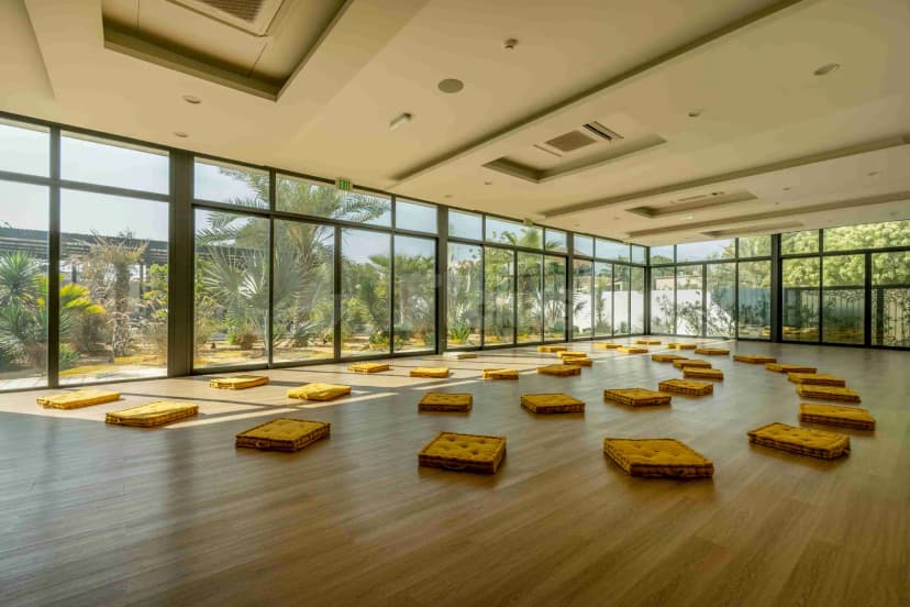 Meeting room at Keyani Wellness in Dubai featuring wooden flooring, floor cushions arranged in rows, and floor-to-ceiling