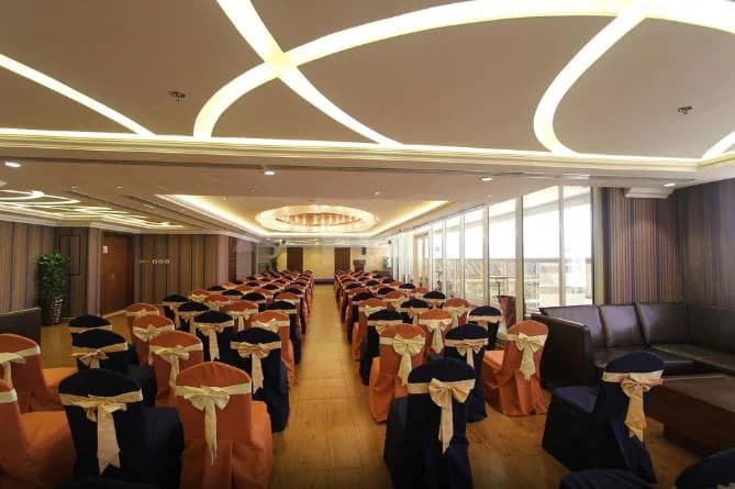 Meeting room at Ivory Grand Hotel Apartments Dubai with rows of chairs, curved ceiling lights, and large windows