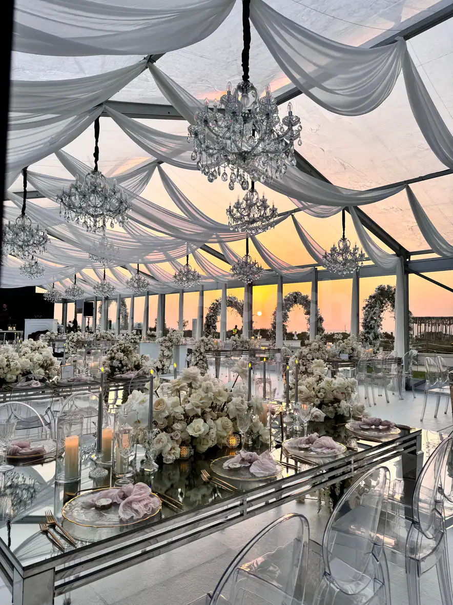 Ballroom at Saadiyat Beach Club in Abu Dhabi with mirrored tables, crystal chandeliers, and draped white ceiling fabric