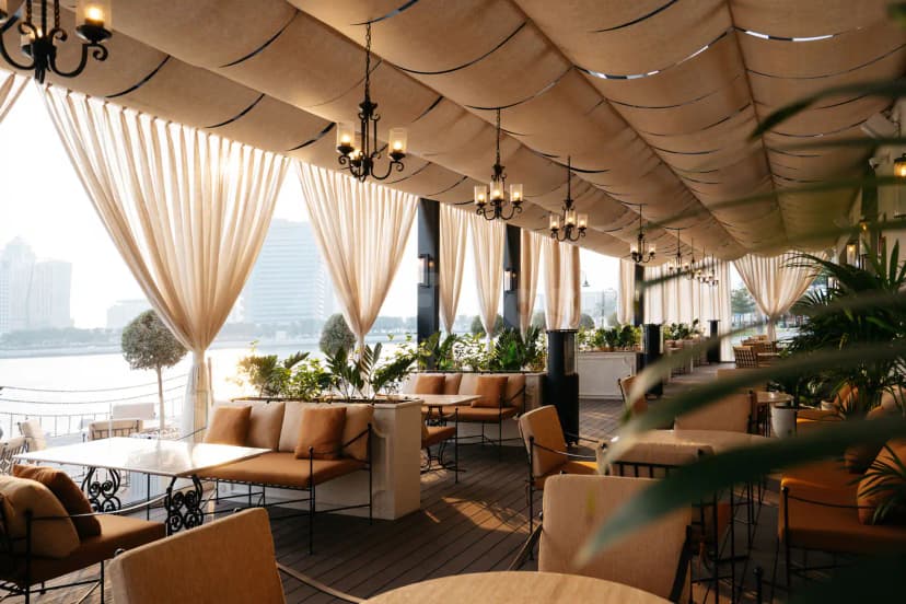 Rooftop terrace at Berenjak Acurio Restaurant Dubai featuring a beige fabric canopy and black wrought iron chandeliers overlooking