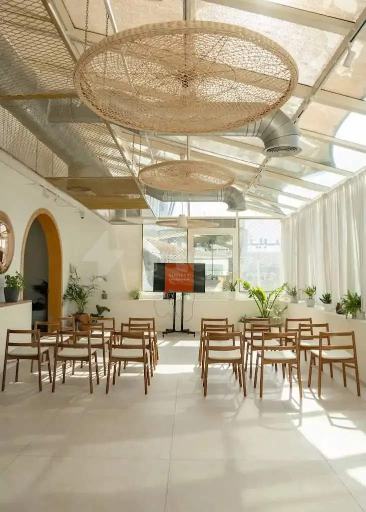 Meeting room at Society Restaurant Abu Dhabi featuring large woven pendant lights and exposed ductwork under a glass