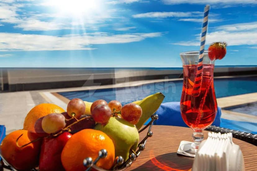 Rooftop terrace at TIME Onyx Hotel Apartments Dubai with fruit basket and red drink beside pool under sunny