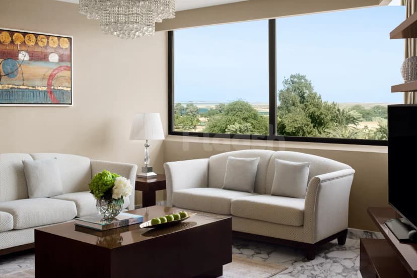Meeting room at InterContinental Al Jubail featuring white patterned sofas, a dark wooden coffee table, and a large