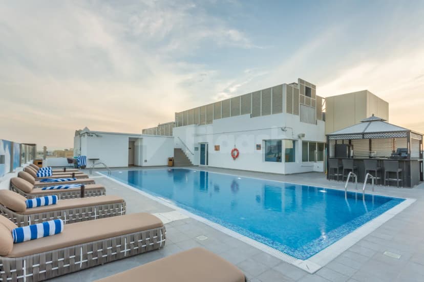 Rooftop terrace at The Avenue Hotel Doha featuring a rectangular pool with blue mosaic tiles and an outdoor