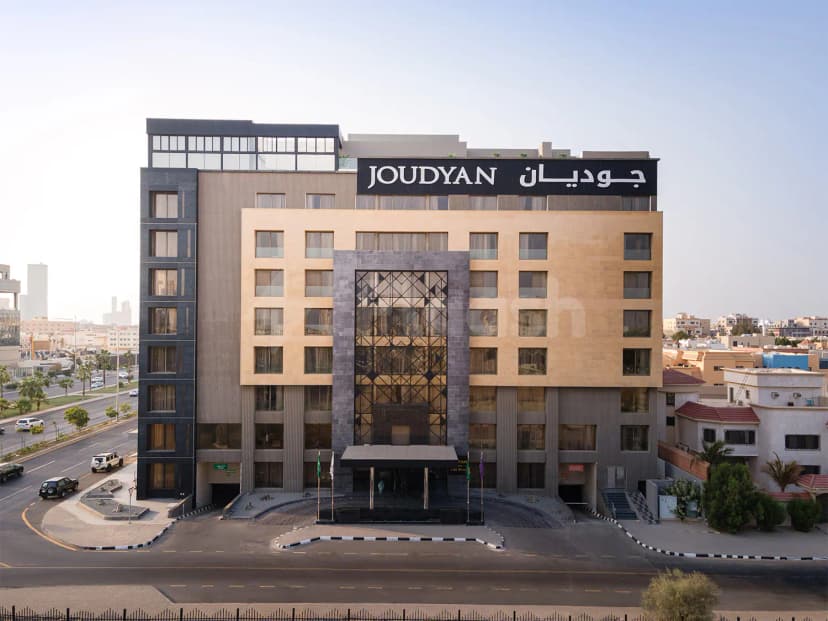 Hotel facade of Joudyan King Road Jeddah by Elaf featuring beige stone, dark grey panels, and a geometric