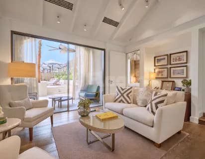 Meeting room at Vera Versilia Dubai featuring a white sofa, beige armchair, and large glass doors opening to