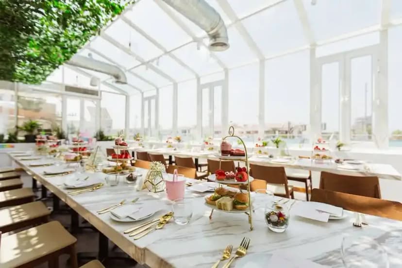 Green leafy ceiling installation at Society Restaurant Abu Dhabi, with marble-top tables and natural light