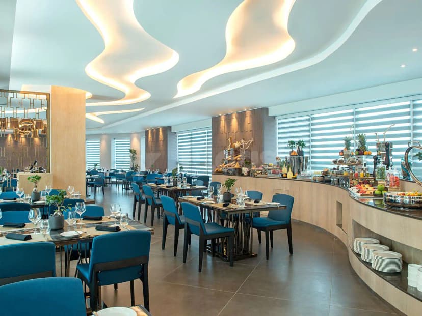 Restaurant at Gulf Court Hotel Business Bay Dubai featuring a curved ceiling with wave-shaped light fixtures