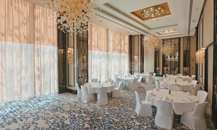 Ballroom at Shaza Doha featuring round tables with white linens, a blue and white patterned carpet, and decorative