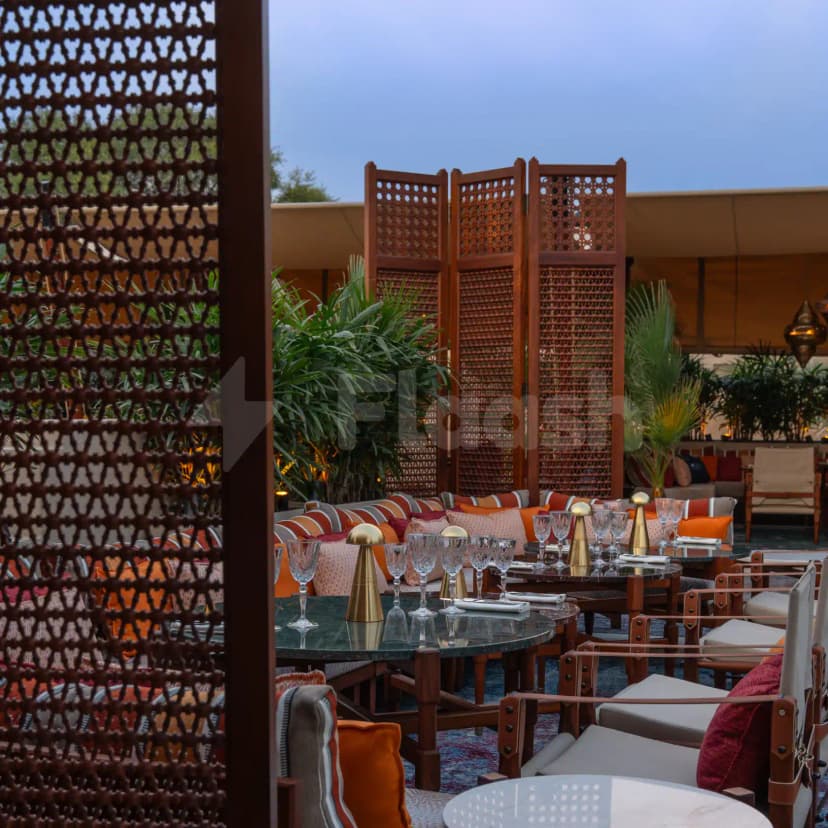 Rooftop terrace at Ninive Bab Al Shams Restaurant Dubai featuring a wooden folding screen and green marble tables