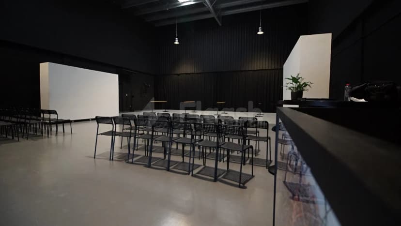 Meeting room at Sima Performing Arts Dubai featuring rows of black metal chairs, a white projection screen