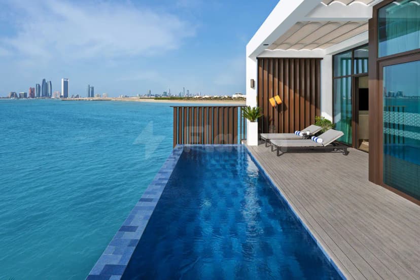 Infinity pool terrace at Bab Al Nojoum Hudayriyat Camp in Abu Dhabi with wooden deck and city skyline