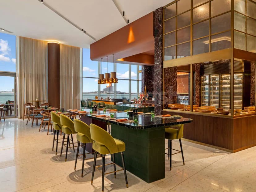 Restaurant at SO Ras Al Khaimah Hotel & Resort featuring a green-tiled bar with black marble countertop