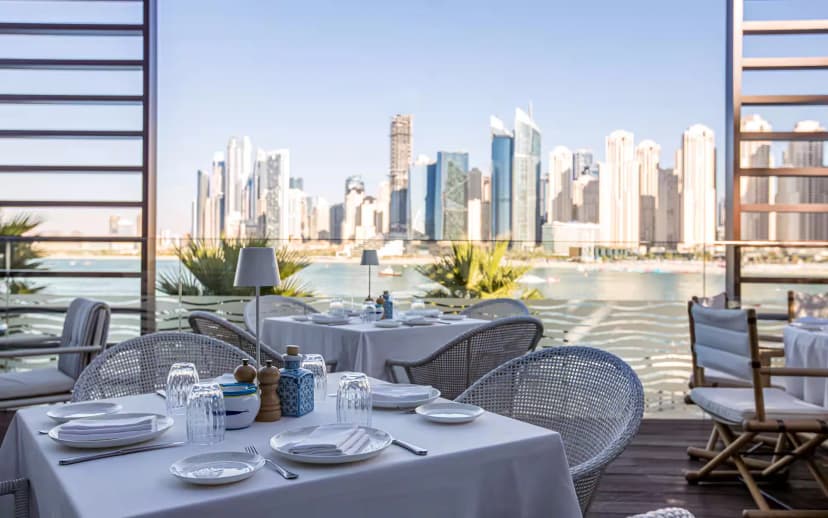 Rooftop terrace at Alici Restaurant Dubai with white table settings and wicker chairs overlooking the Dubai skyline