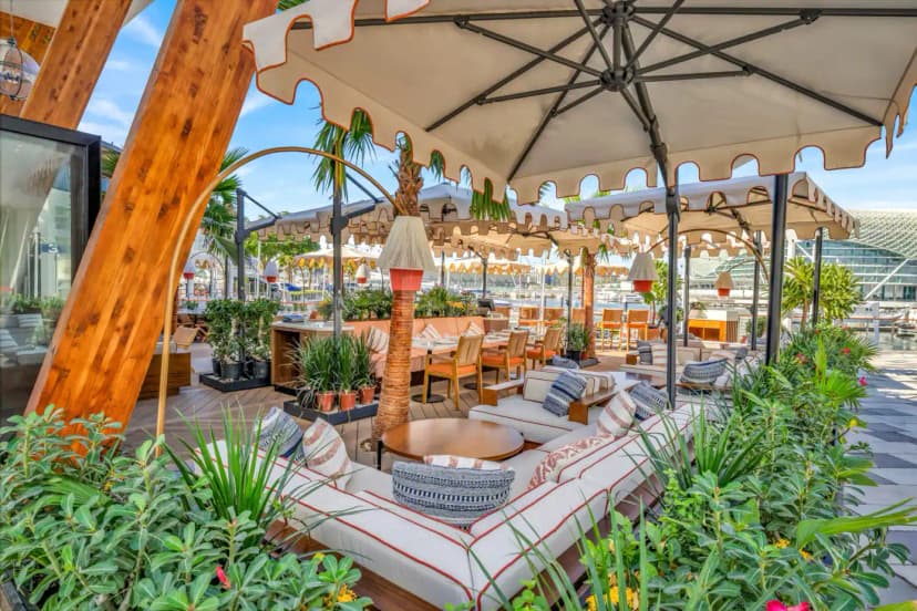 Rooftop terrace at Mika Restaurant Abu Dhabi featuring white cushioned sofas with red trim and large beige umbrellas