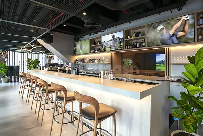 Bar counter at Bedrock Pier 7 in Dubai featuring backlit shelves with framed golf photos and a large