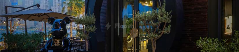 Rooftop terrace at Shi Restaurant Dubai Marina featuring a black glossy sculpture and potted olive trees with Dubai