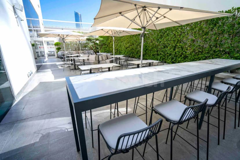 Rooftop terrace at Form Hotel Dubai in Dubai with marble-top bar and green hedge wall