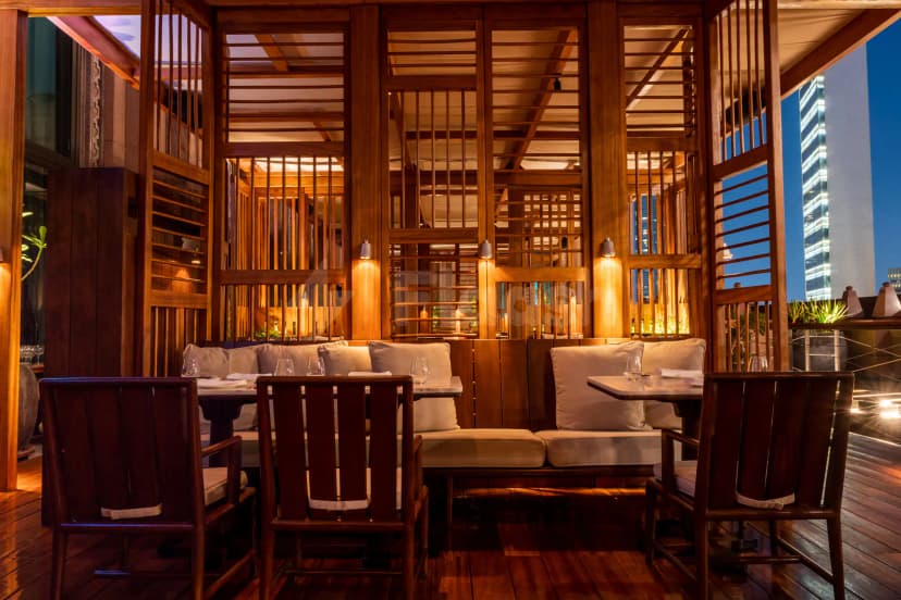 Rooftop terrace at Hakkasan Abu Dhabi featuring wooden lattice screens and a city skyline view at dusk