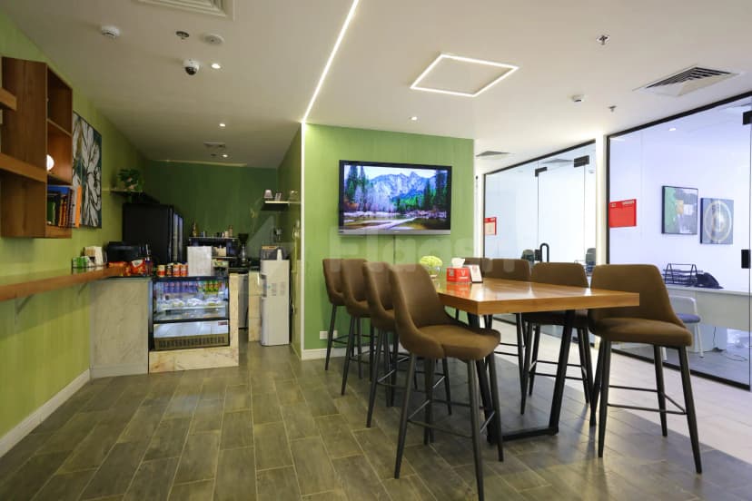 Restaurant at Vision Work Space Jeddah featuring a wooden table with brown stools, green accent wall, and mounted
