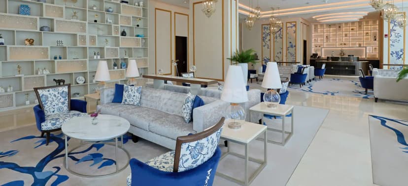 Entrance hall at Shaza Doha featuring a reception desk, built-in shelving with decorative items, and blue-and-white patterned