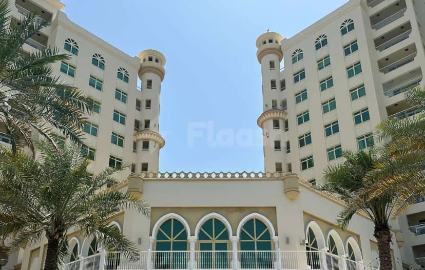 Hotel facade of Cabana On The Beach Palm Dubai featuring twin circular turrets and arched green-framed windows under