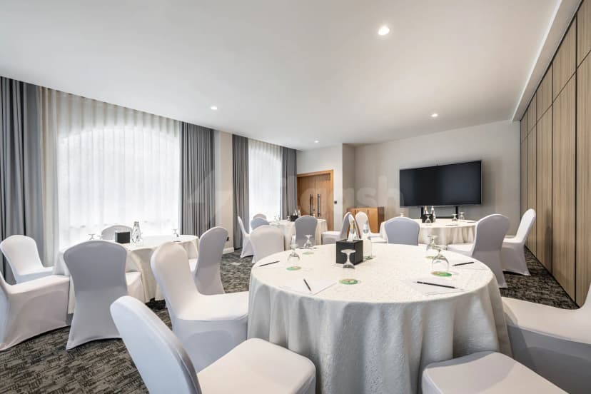 Meeting room at Intercity Hotel Riyadh with round tables set for conferences, white chair covers, and a wall-mounted