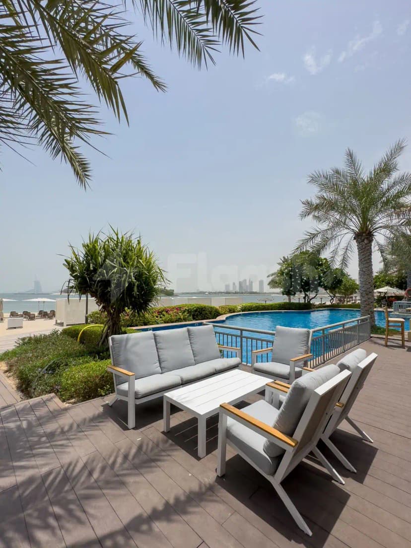 Terrace at Cabana On The Beach Palm Dubai featuring a wooden deck, pool, palm trees, and distant city