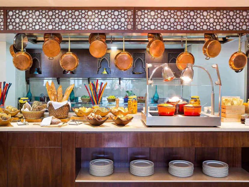 Buffet counter at Al Liwan Restaurant Ras Al Khaimah featuring hanging copper pots and an ornate wooden lattice