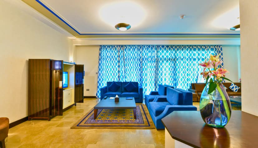 Meeting room at Retaj Salwa Resort & Spa in Doha featuring blue sofas, patterned curtains, and a polished stone