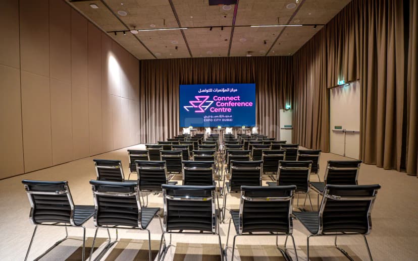 Meeting room at The Nexus, Expo City Dubai, featuring rows of black chairs and a large digital screen