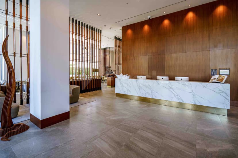 Entrance hall at Form Hotel Dubai featuring a marble reception desk with brass base and wooden wall paneling