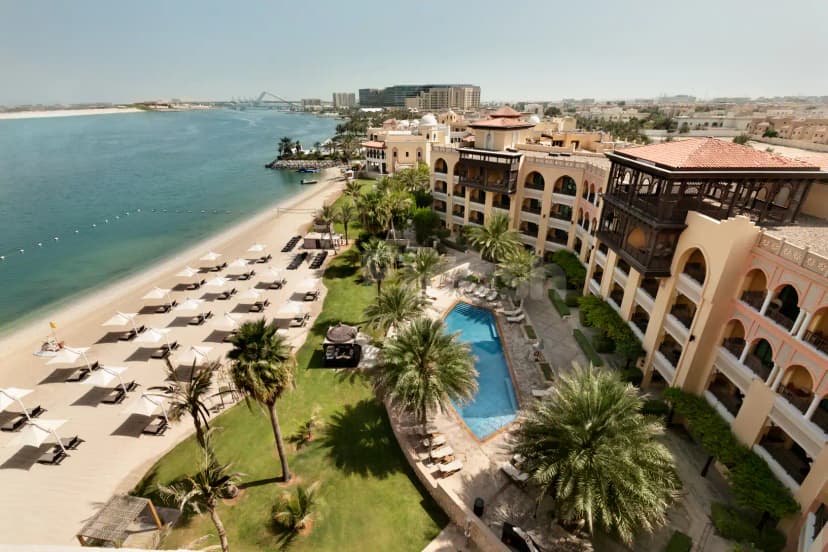 Rooftop terrace at Shangri-La Qaryat Al Beri Abu Dhabi featuring a blue swimming pool, green palm trees