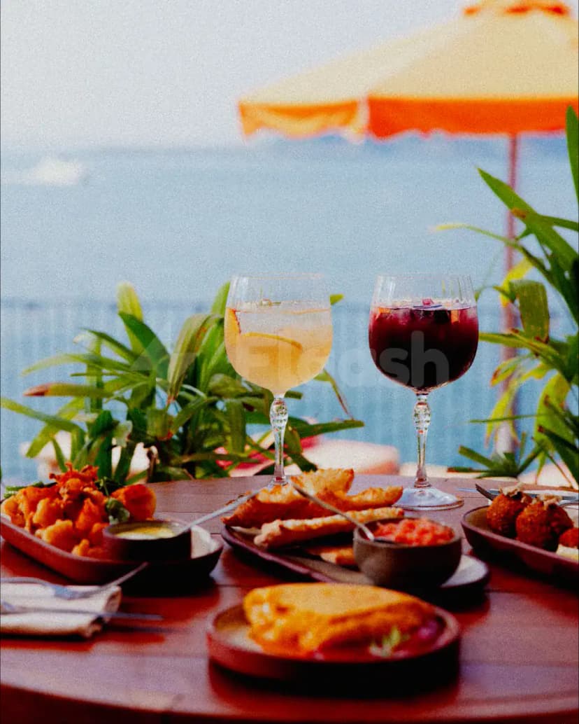 Rooftop terrace at Tagomago Dubai featuring a wooden table set with two wine glasses and green plants, overlooking