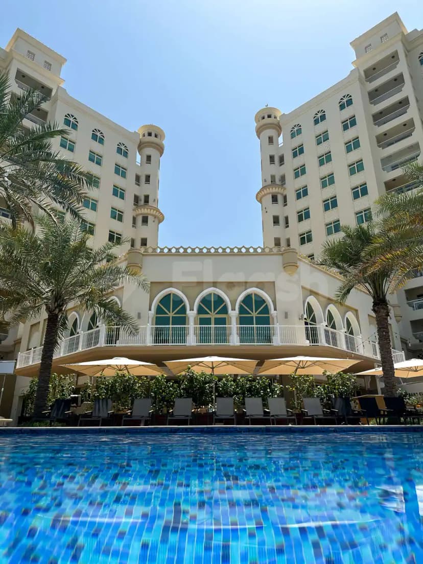 Swimming pool at Cabana On The Beach Palm Dubai with arched windows and palm trees