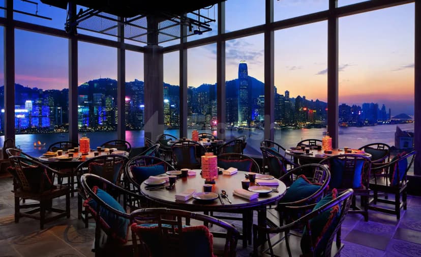 Restaurant interior at Hutong Dubai with round wooden tables, dark chairs, and large windows overlooking the Dubai skyline