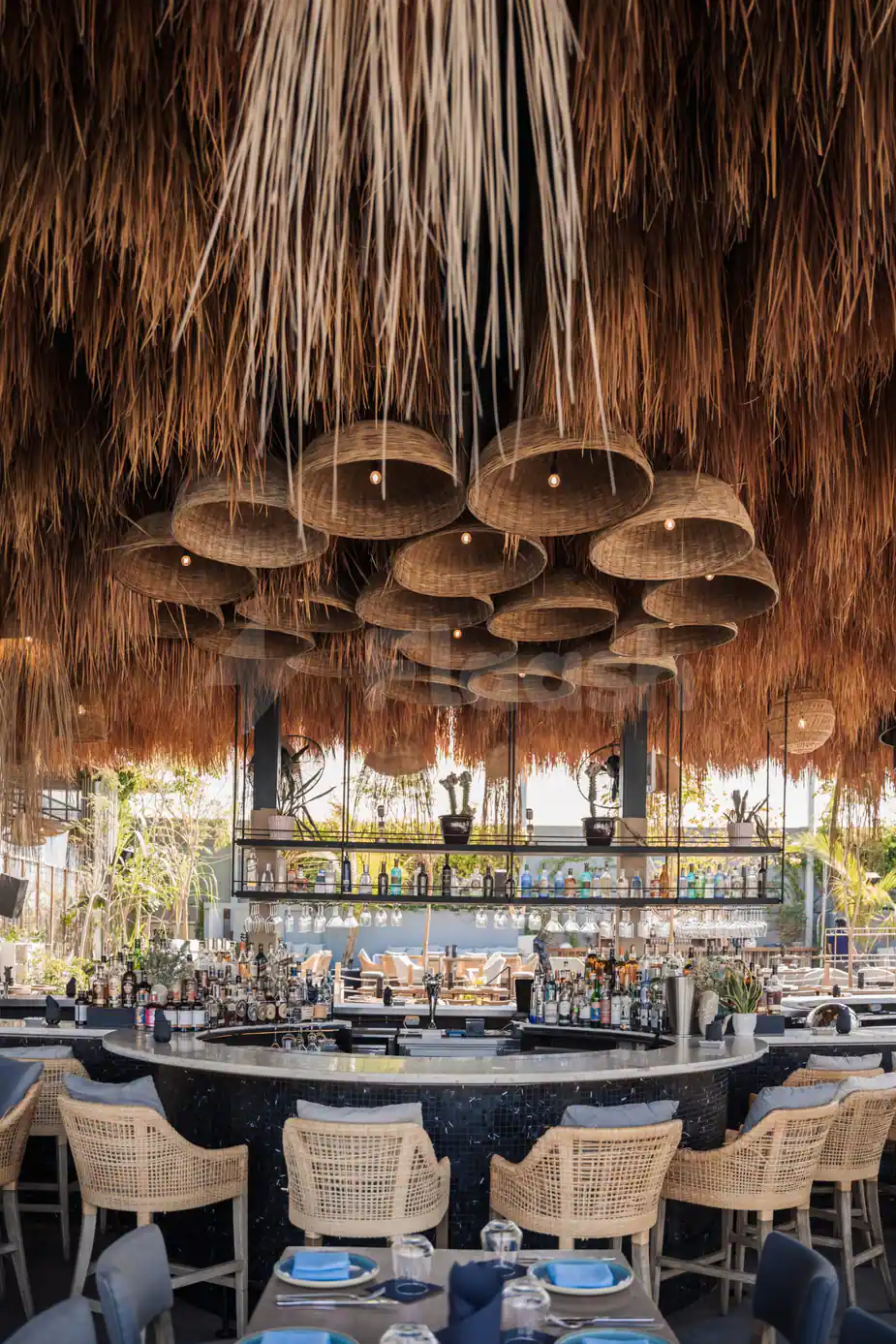 Thatched ceiling with wicker pendant lights above a curved bar counter at Bar Du Port Dubai