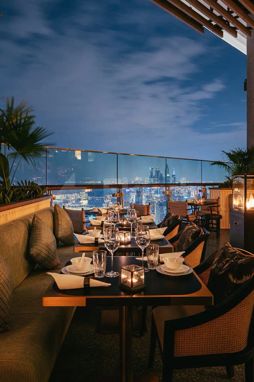 Rooftop terrace at Mott 32 Dubai featuring glass railings and a panoramic city skyline view at dusk