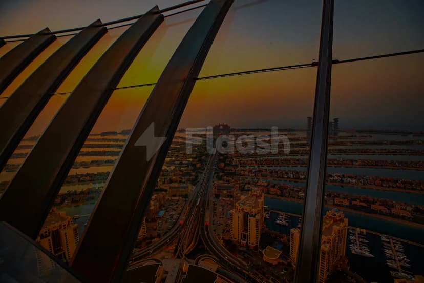 Rooftop terrace at Coucou Dubai with glass railing and metal frame overlooking Palm Jumeirah, waterways, and cityscape