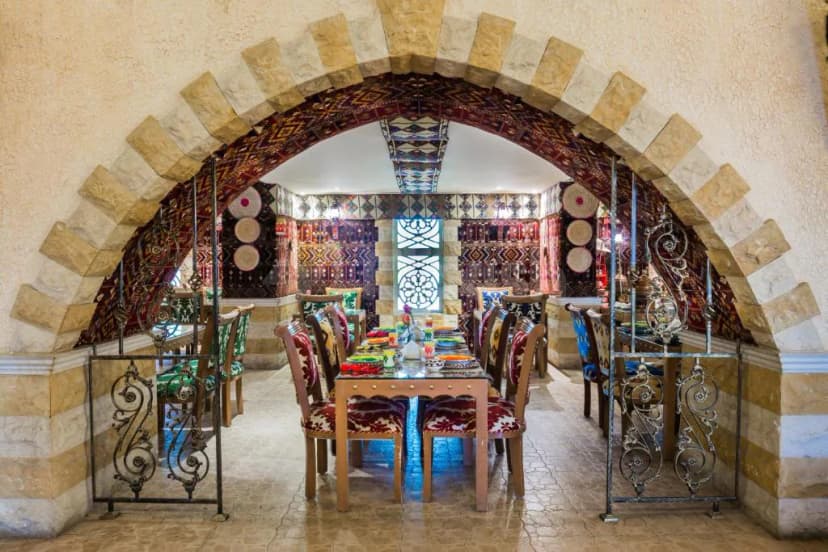 Restaurant at Mena Plaza Hotel Albarsha Dubai featuring a stone archway and ornate metal gate framing the dining
