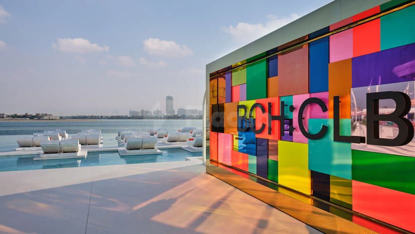 Rooftop terrace at BCH CLB Dubai featuring a colorful glass wall with black 3D lettering and an infinity