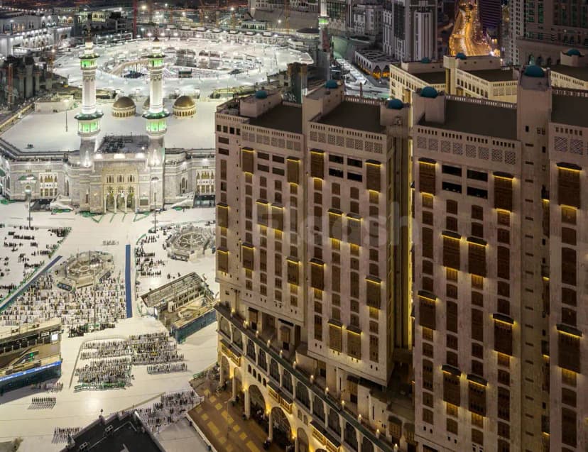 Hotel facade of Makkah Towers Al Khalil in Makkah, featuring stone cladding, arched windows, blue domes, and warm