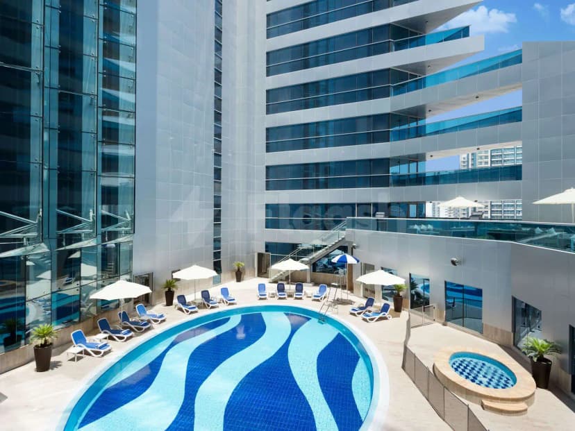 Oval swimming pool at Gulf Court Hotel Business Bay Dubai with blue mosaic wavy tile pattern and white