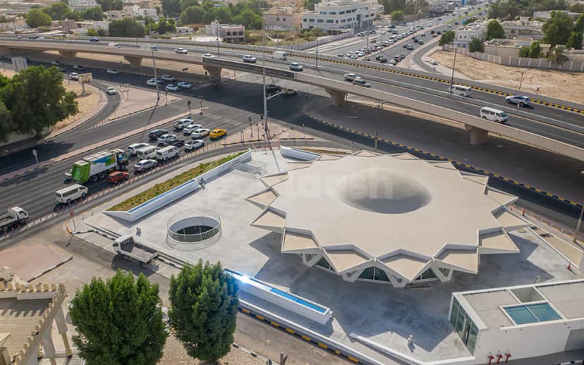 Star-shaped concrete facade of The Flying Saucer Sharjah with a central circular skylight and a landscaped planter