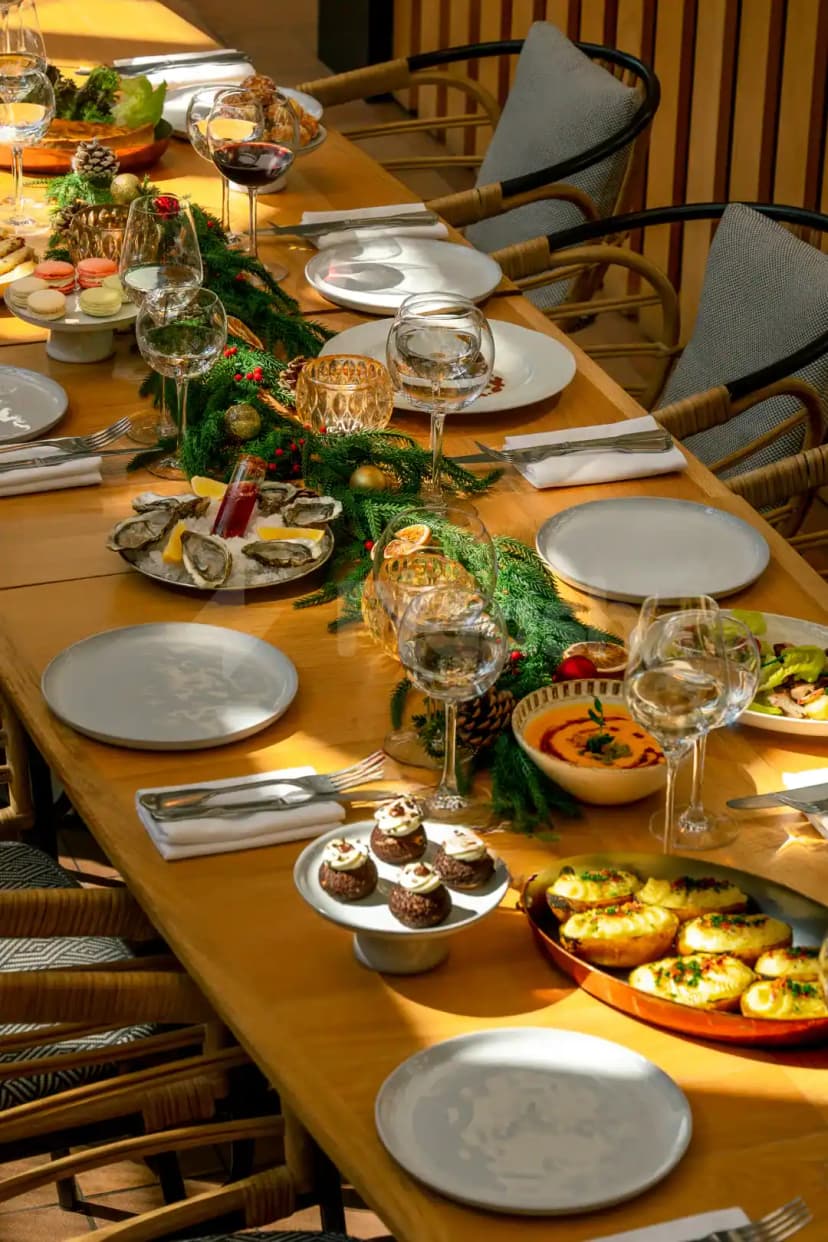 Long wooden table at Eugène Eugène Restaurant Dubai set for a festive meal with oyster platter